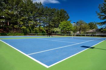 a tennis court with trees in the background at Crestmont at Thornblade, Greenville